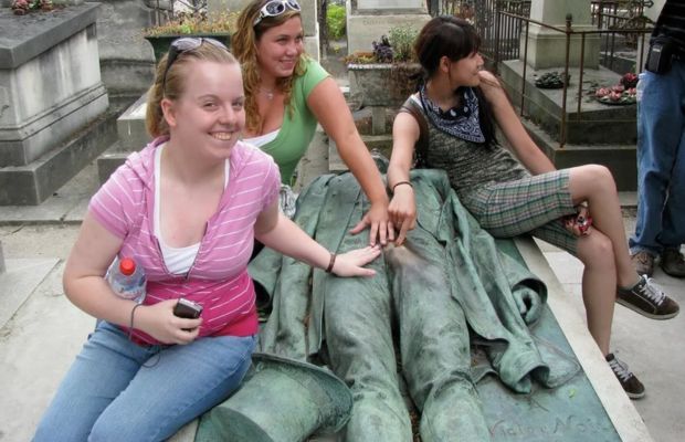 Estatua em cima do tumulo é assediada por inúmeras mulheres todas funerárias